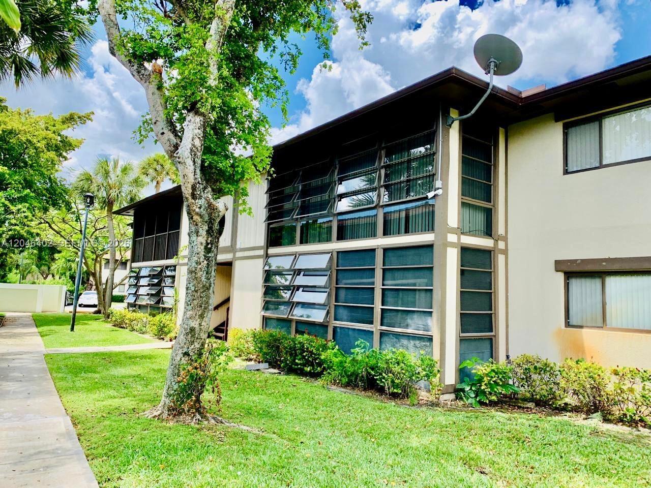 A two-story apartment building exterior features jalousie windows and a satellite dish on the roof — 809 NE 199th St # 7, Miami FL 33179, MIAMI, FL