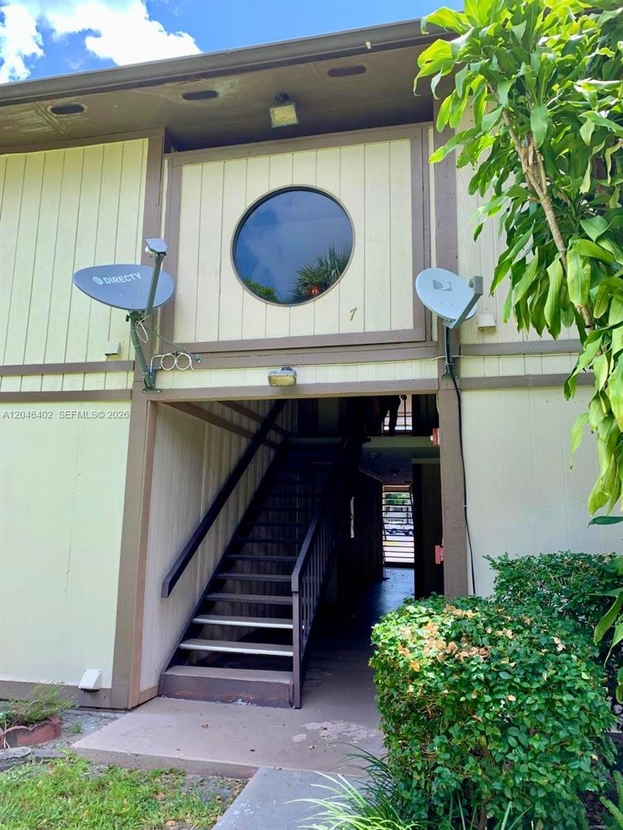 An exterior view of a building entrance with a staircase leading to upper units — 809 NE 199th St # 7, Miami FL 33179, MIAMI, FL