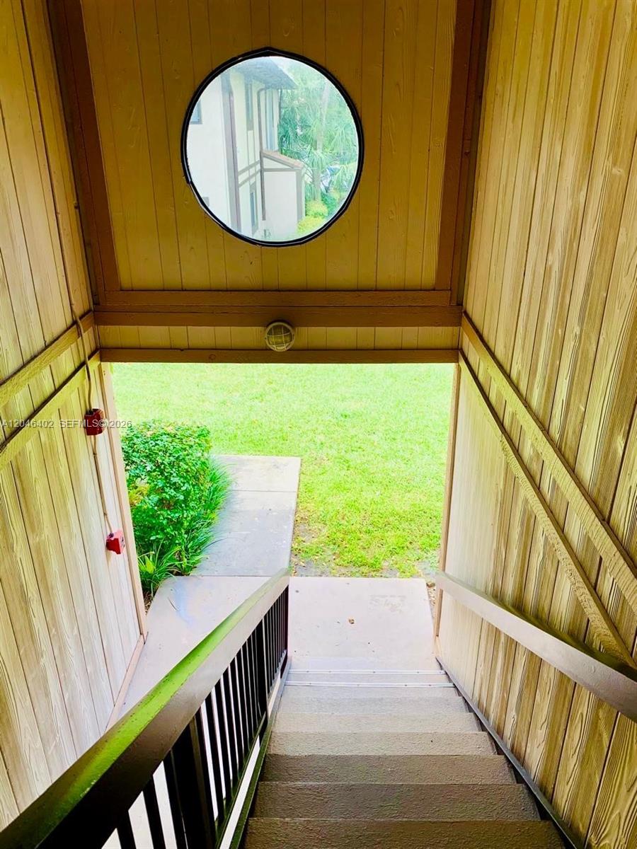 An outdoor staircase with wooden walls leads down to a grassy area — 809 NE 199th St # 7, Miami FL 33179, MIAMI, FL