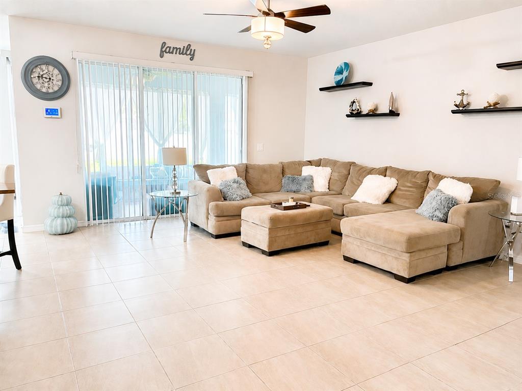 A living room features a large beige sectional sofa, tile flooring, and wall-mounted shelving — 5254 SE 91ST STREET, OCALA, FL