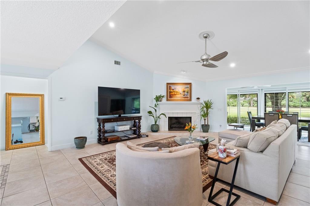 A living room features a fireplace, a television on a console, and light-colored tile flooring — 110 Prestwick Circle, Vero Beach FL 32967, VERO BEACH, FL
