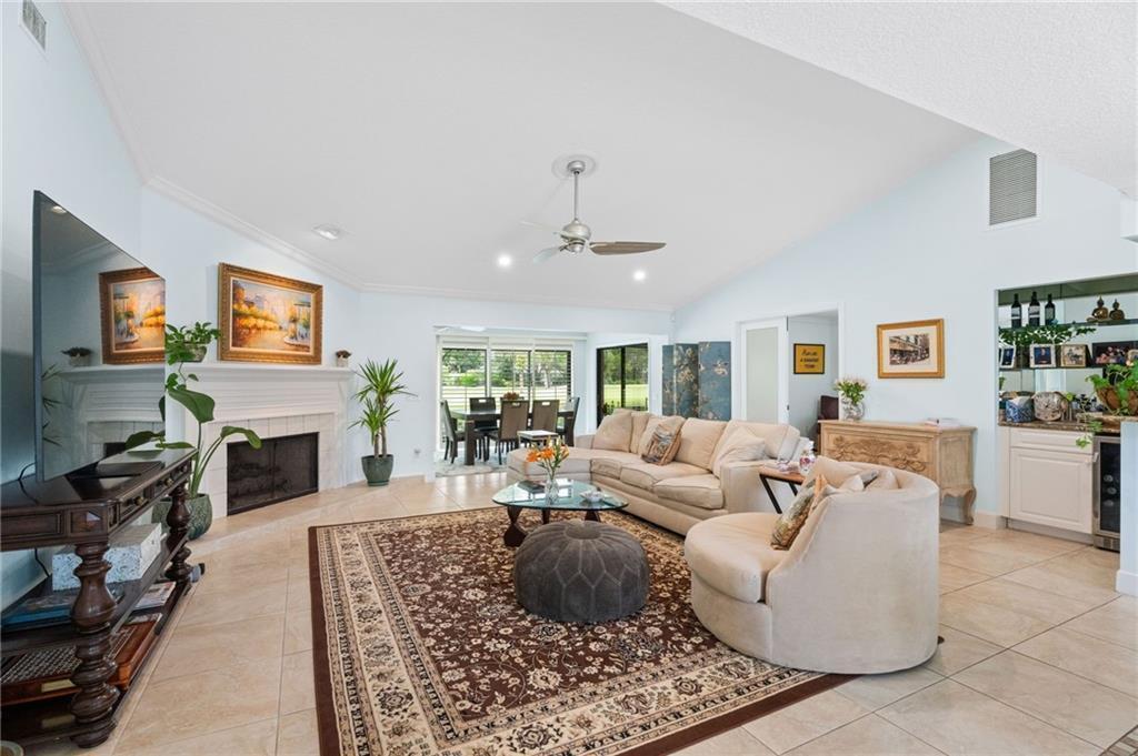 A spacious living room features a fireplace, a large area rug, and a dining area — 110 Prestwick Circle, Vero Beach FL 32967, VERO BEACH, FL