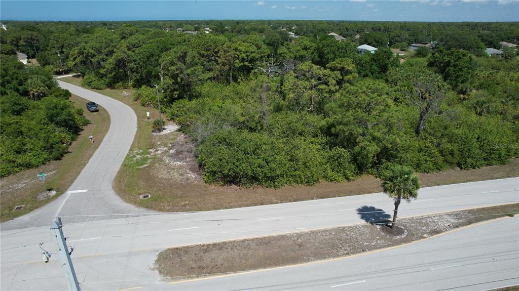 An aerial view shows a vacant, wooded lot situated at the corner of two roads — 142 LOMAS ROAD, ROTONDA WEST, FL