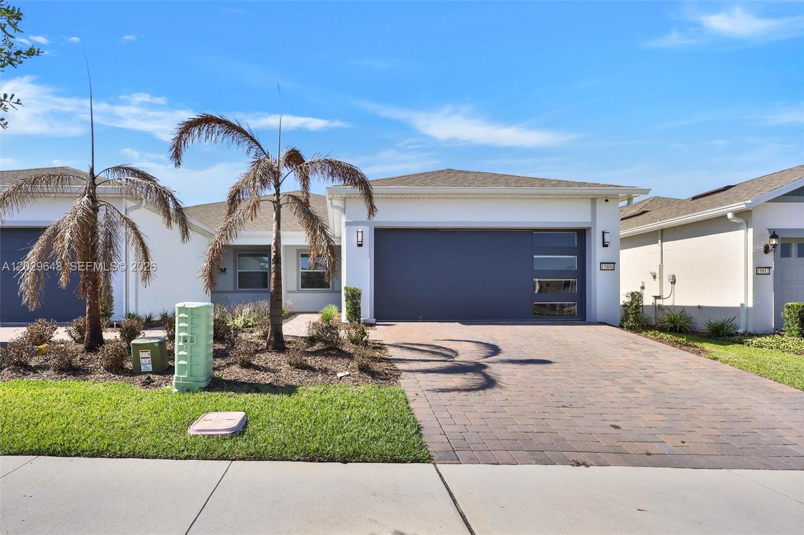A single-story house features a paved driveway, a dark garage door, and a palm tree — 15806 GEM VIEW ST, Winter Garden FL 34787, WINTER GARDEN, FL