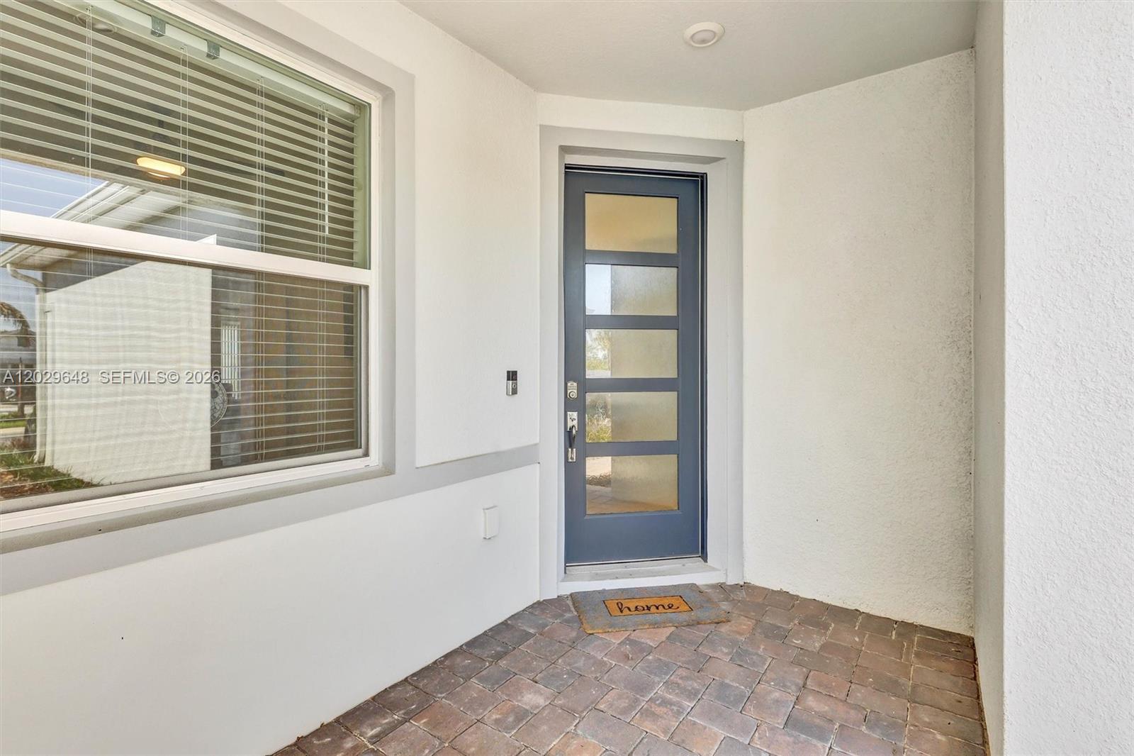 A blue front door with horizontal glass panels sits on a brick-paved entryway porch — 15806 GEM VIEW ST, Winter Garden FL 34787, WINTER GARDEN, FL