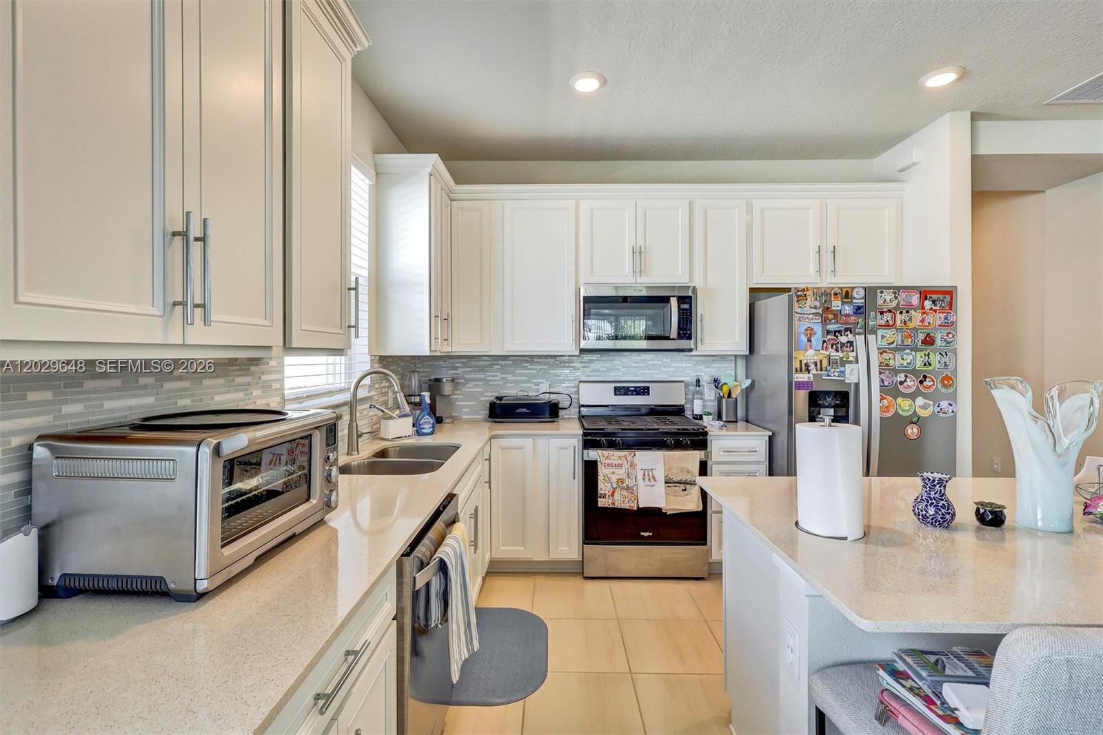 A kitchen features white cabinets, stainless steel appliances, a center island, and light-colored countertops — 15806 GEM VIEW ST, Winter Garden FL 34787, WINTER GARDEN, FL