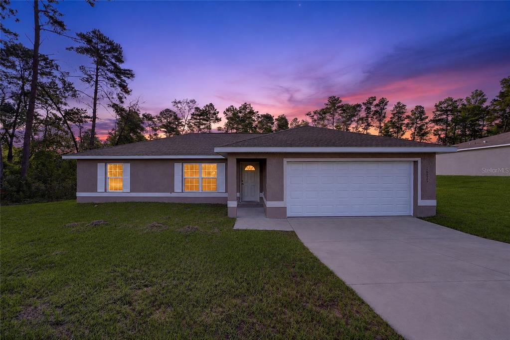 A single-story house with a two-car garage and a concrete driveway at sunset — 16993 SW 20 COURT ROAD, OCALA, FL