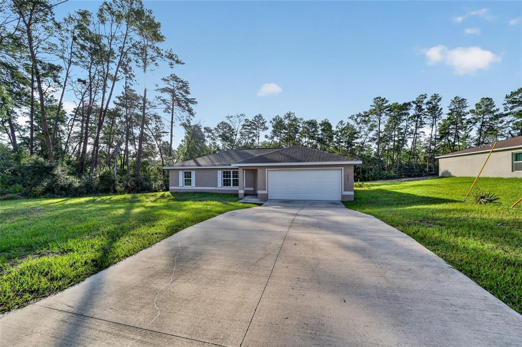 A single-story house with a two-car garage and a concrete driveway sits on a lawn — 16993 SW 20 COURT ROAD, OCALA, FL