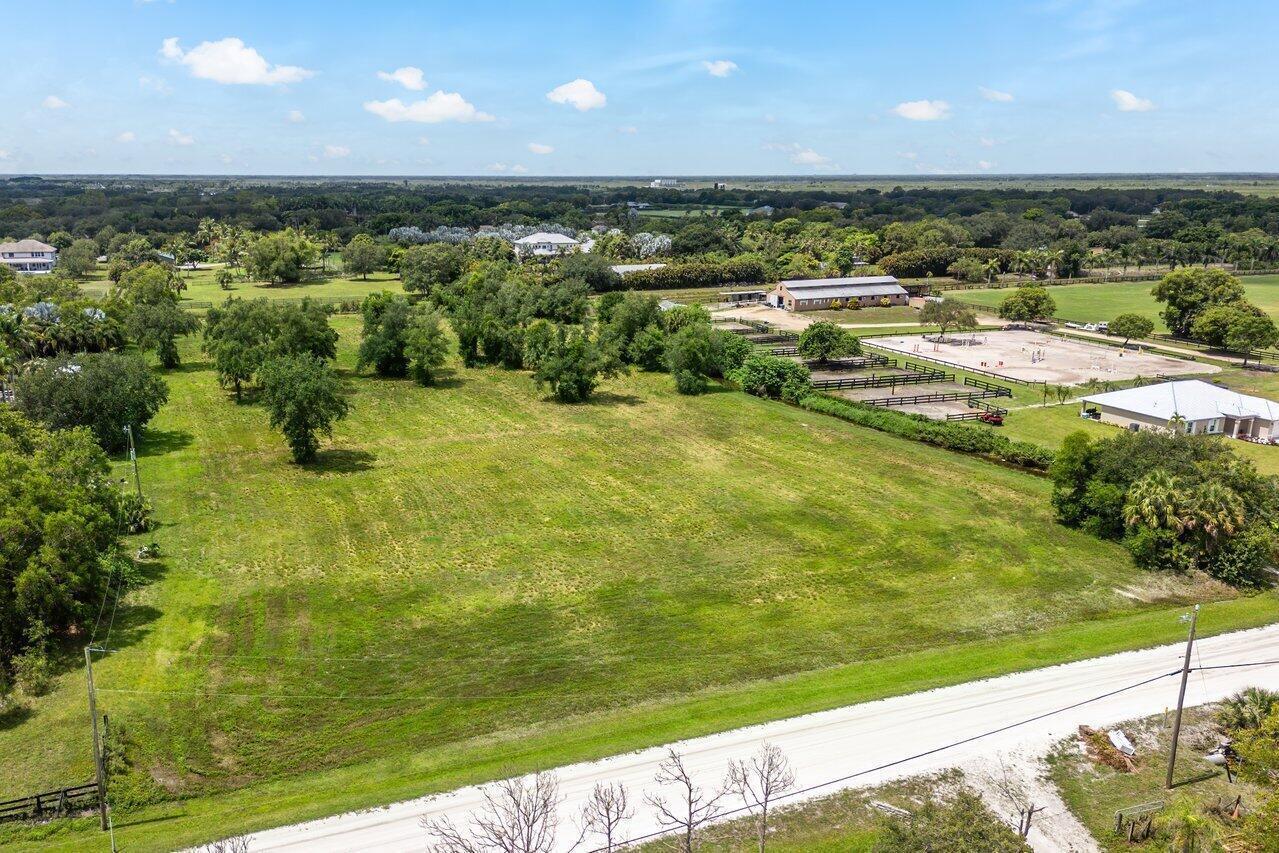 An aerial view shows a large, grassy vacant lot adjacent to a horse stable facility — 16526 Hollow Tree Lane, Wellington FL 33470, WELLINGTON, FL