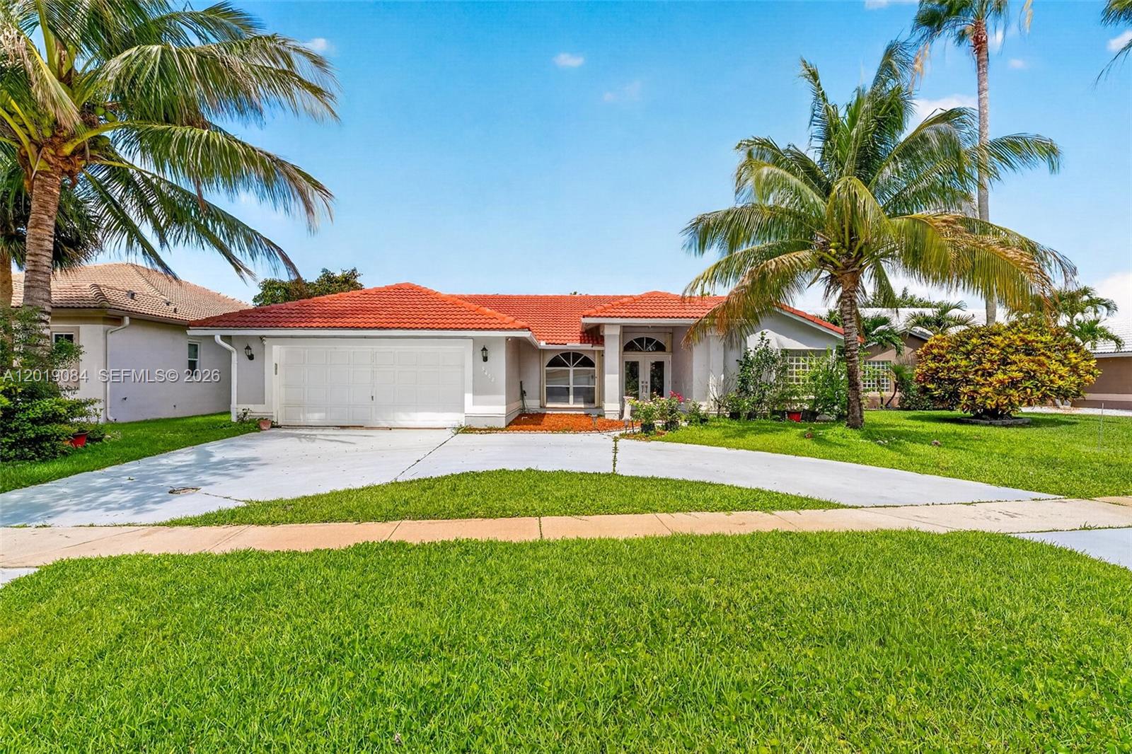 A single-story house with a red tile roof, white garage, and palm trees in front — 3462 Harness Cir, Wellington FL 33449, WELLINGTON, FL