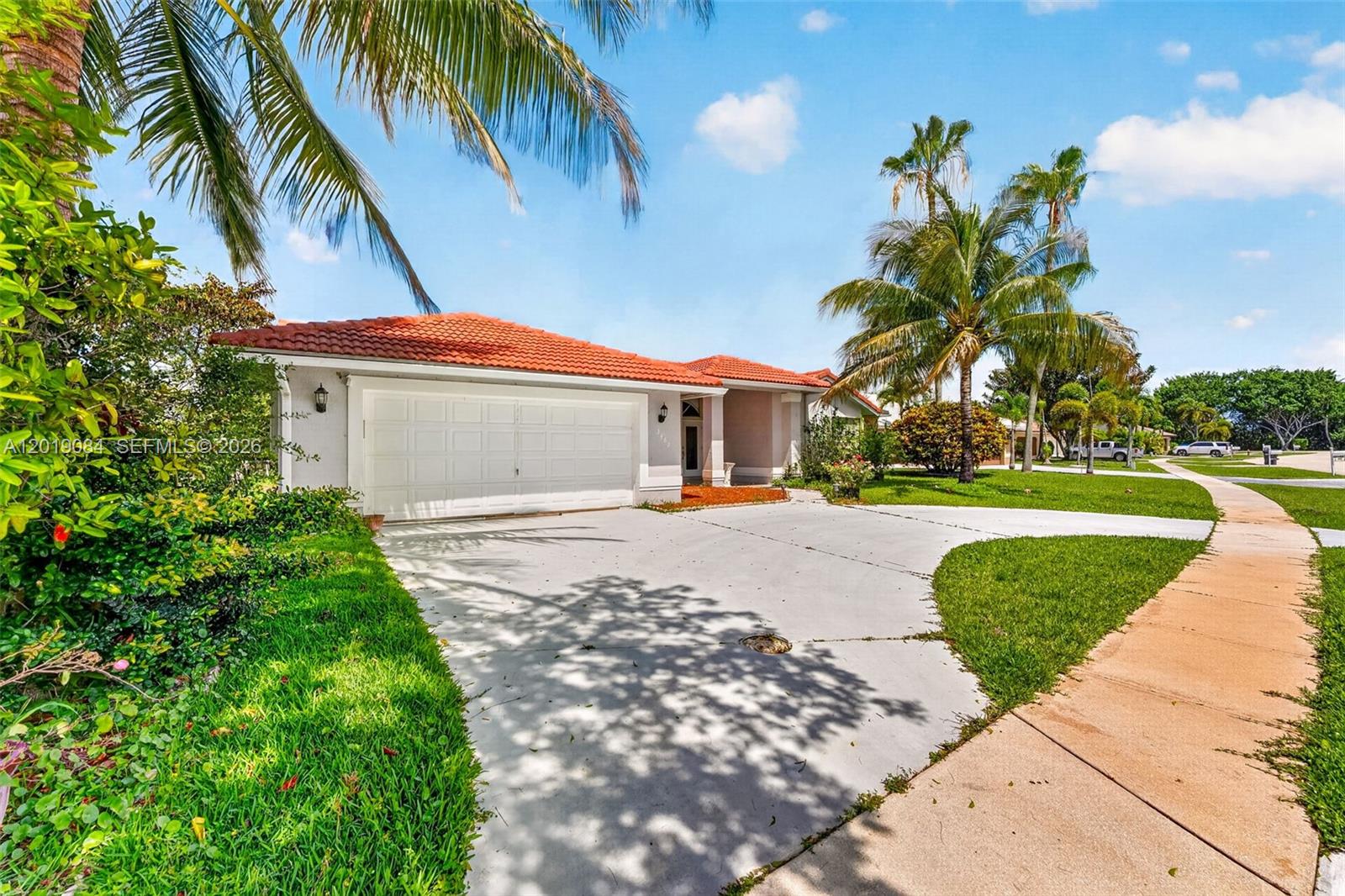 A single-story house with a white garage, red tile roof, and palm trees — 3462 Harness Cir, Wellington FL 33449, WELLINGTON, FL