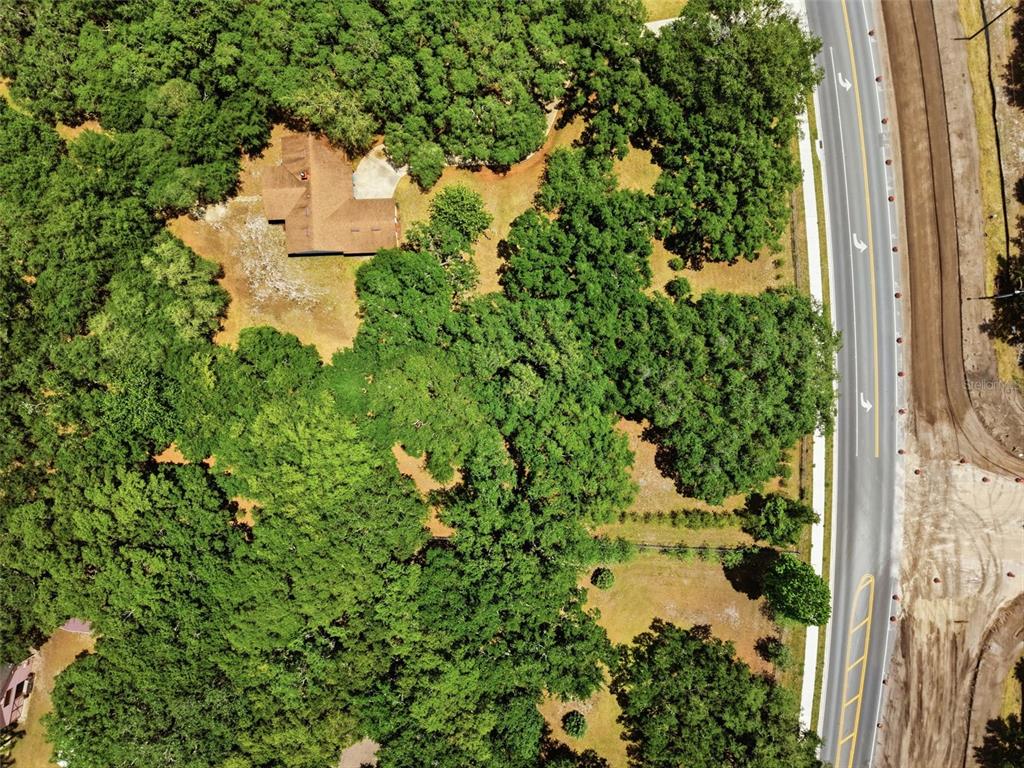 An aerial view shows a house nestled in a wooded lot beside a paved road — 4275 BOGGY CREEK ROAD, KISSIMMEE, FL
