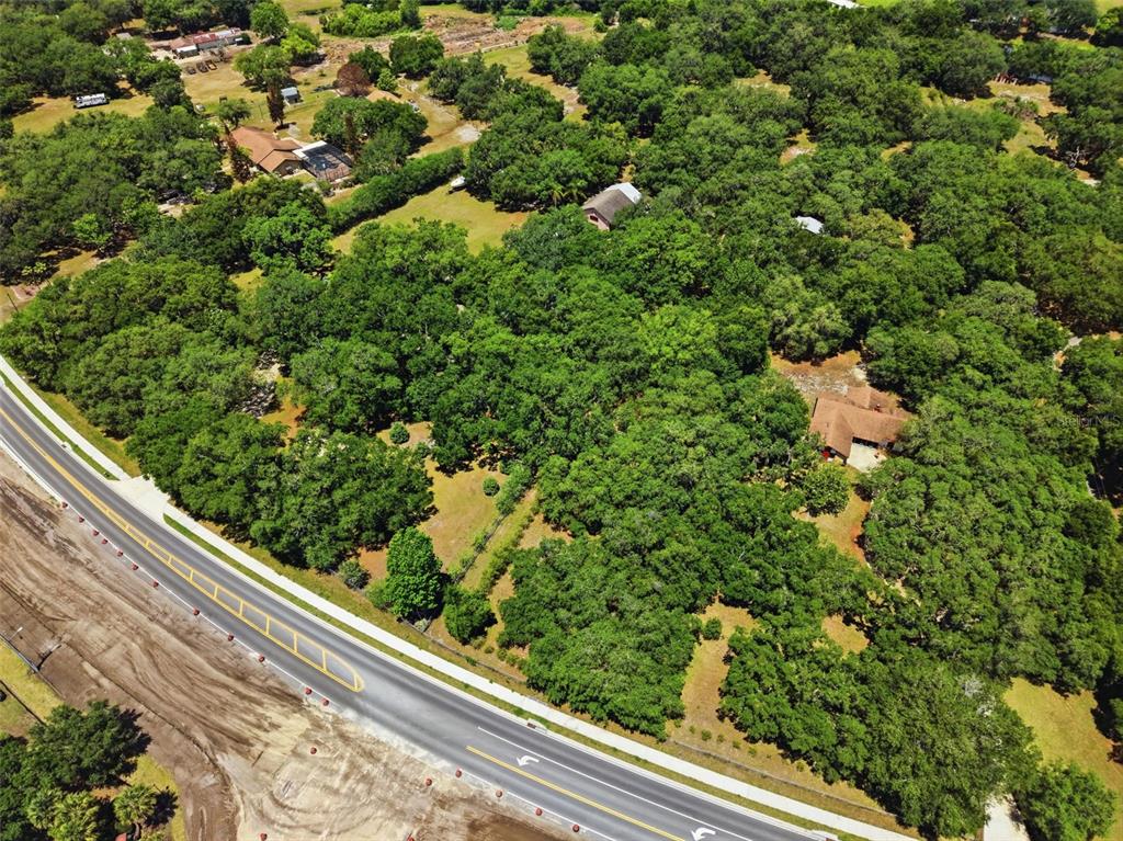 An aerial view shows a wooded property with two houses situated along a paved road — 4275 BOGGY CREEK ROAD, KISSIMMEE, FL