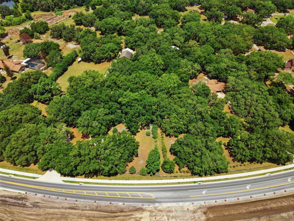 An aerial view shows a wooded lot bordered by a curved road and nearby houses — 4275 BOGGY CREEK ROAD, KISSIMMEE, FL