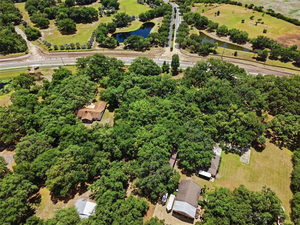 An aerial view shows a wooded property with several buildings, a pond, and a road — 4275 BOGGY CREEK ROAD, KISSIMMEE, FL