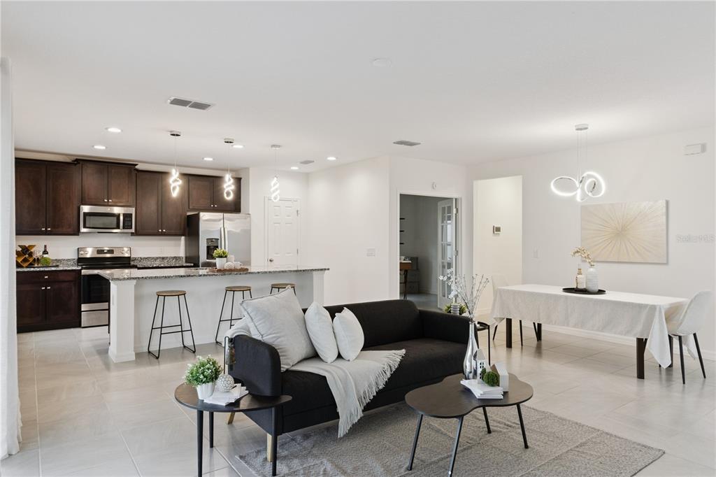 An open-concept living area features a kitchen with dark cabinets, a sofa, and dining table — 779 SCRUB OAK HAMMOCK ROAD, DAVENPORT, FL