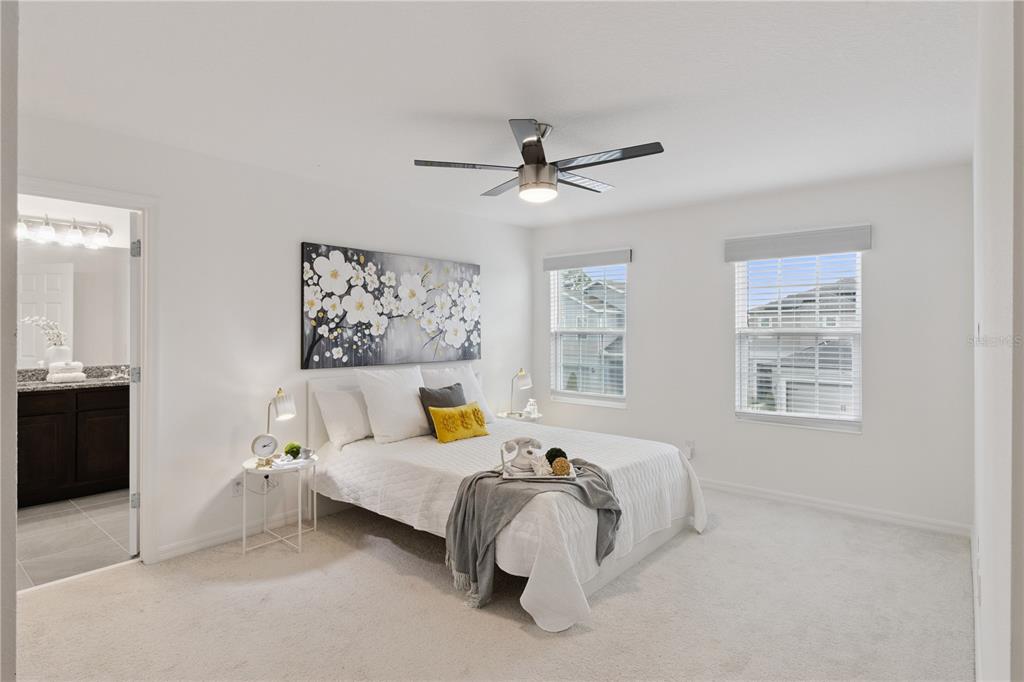A bedroom features a white bed, floral wall art, a ceiling fan, and an attached bathroom — 779 SCRUB OAK HAMMOCK ROAD, DAVENPORT, FL