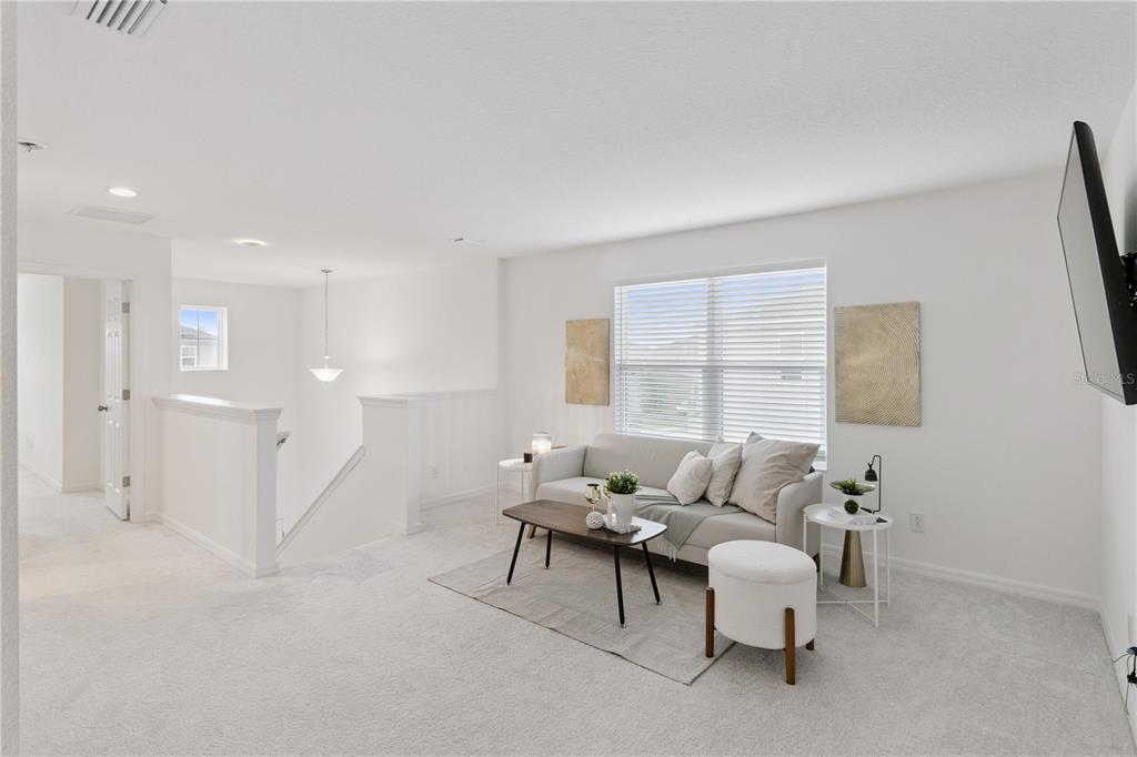 A bright loft area features white walls, light carpeting, a sofa, and a staircase railing — 779 SCRUB OAK HAMMOCK ROAD, DAVENPORT, FL