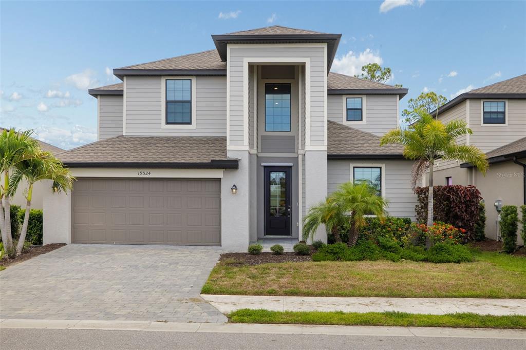 A two-story suburban house features a gray exterior, a two-car garage, and a front entryway — 19524 FISHHAWK TRAIL, VENICE, FL