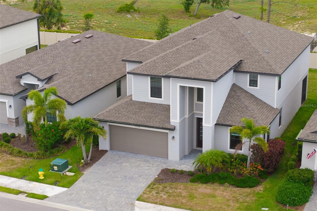 An aerial view shows a two-story gray house with a paved driveway and palm trees — 19524 FISHHAWK TRAIL, VENICE, FL