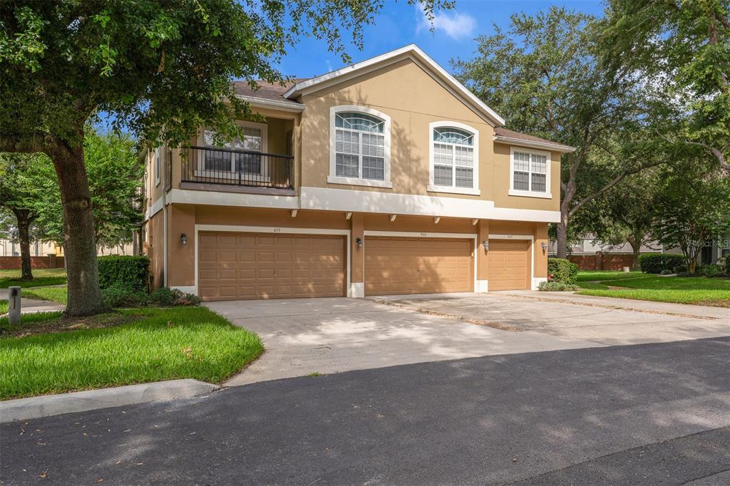 A two-story residential building with three garage doors and a second-floor balcony — 870 ASHWORTH OVERLOOK DRIVE UNIT A, APOPKA, FL