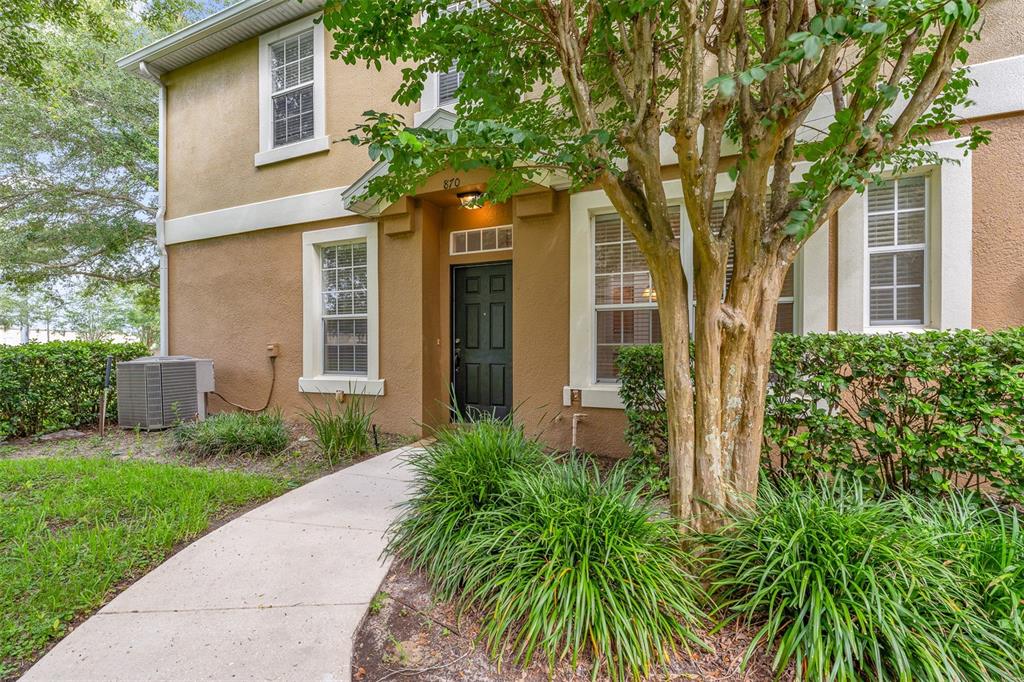 A tan two-story townhouse building with three garage doors and a second-floor balcony — 870 ASHWORTH OVERLOOK DRIVE UNIT A, APOPKA, FL