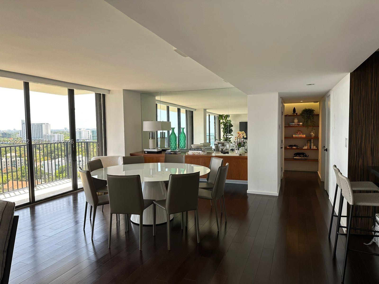 A dining area with a round white table, grey chairs, and dark hardwood floors — 1450 Brickell Bay Dr # 1907, Miami FL 33131, MIAMI, FL