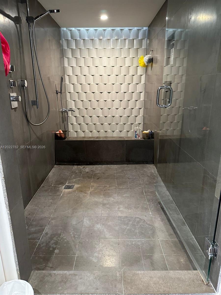A walk-in shower features dark tile walls, a textured accent wall, and a built-in bench — 1450 Brickell Bay Dr # 1907, Miami FL 33131, MIAMI, FL