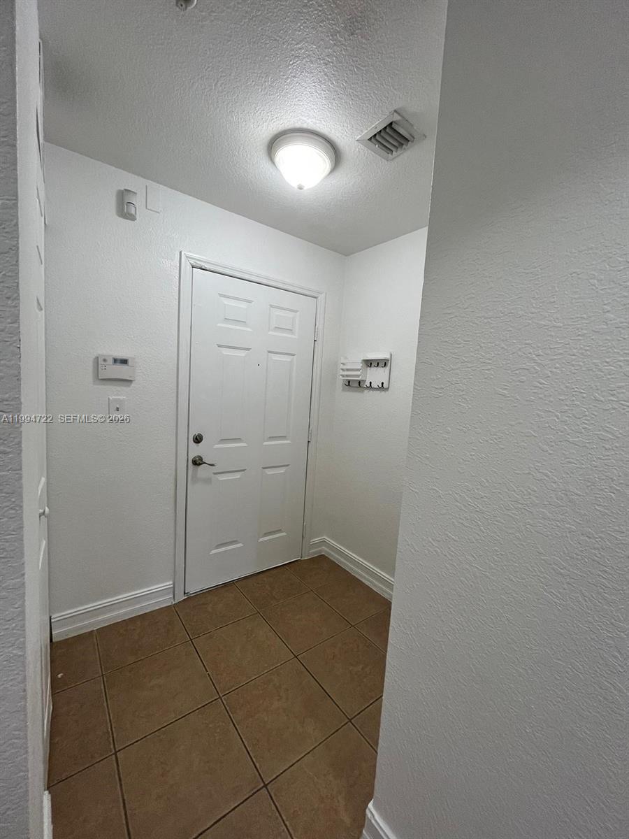 A small entryway features a white door, tiled flooring, and a wall-mounted key rack — 7995 NW 8th St # 115, Miami FL 33126, MIAMI, FL