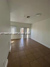 An empty room with light-colored walls, brown tile flooring, and a sliding glass door — 7995 NW 8th St # 115, Miami FL 33126, MIAMI, FL