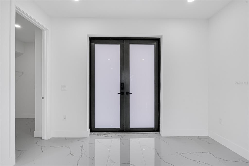 A room with white walls, marble-look tile flooring, and a black-framed double glass door — 153 AUSTRALIAN DRIVE, ROTONDA WEST, FL