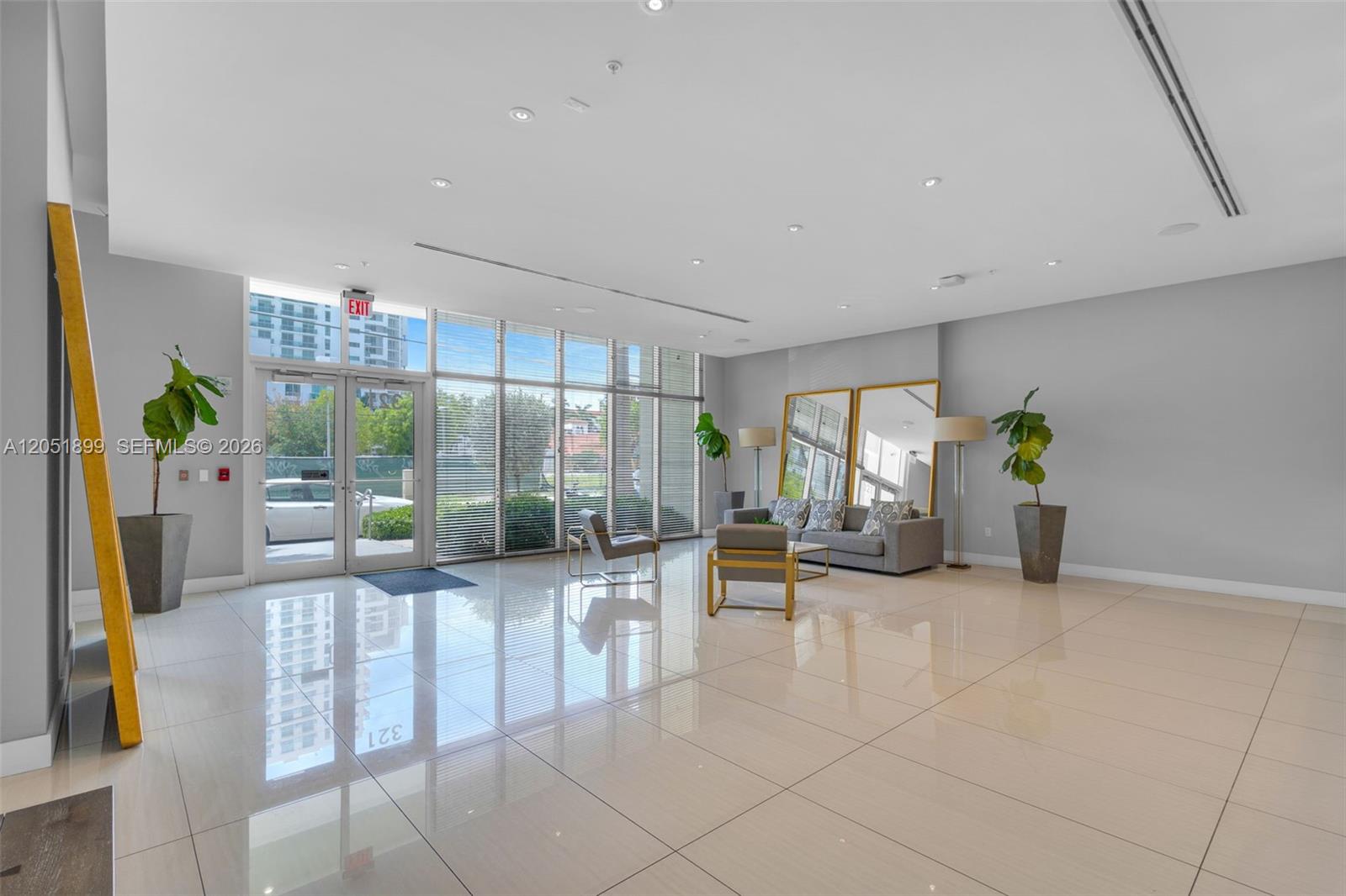 A modern, spacious lobby features polished tile floors, floor-to-ceiling windows, and minimalist seating — 321 NE 26th St # 709, Miami FL 33137, MIAMI, FL