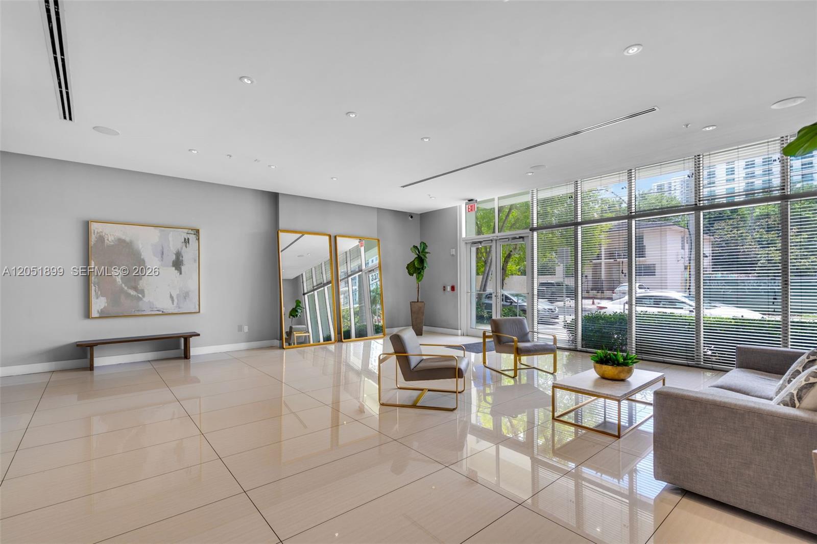 A modern lobby features light tile floors, floor-to-ceiling windows, and contemporary seating furniture — 321 NE 26th St # 709, Miami FL 33137, MIAMI, FL