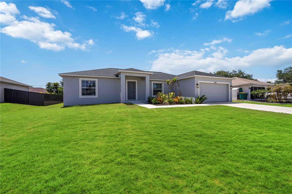 A single-story gray house with a two-car garage and a large front lawn — 7089 PLANTATION STREET, ENGLEWOOD, FL