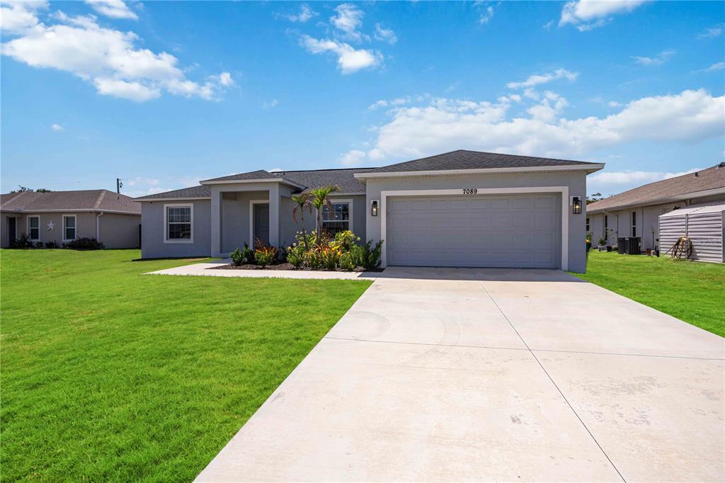 A single-story house with a gray exterior, a two-car garage, and a concrete driveway — 7089 PLANTATION STREET, ENGLEWOOD, FL