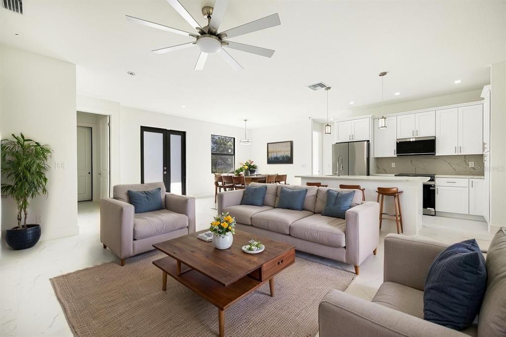 An open-concept living room and kitchen featuring white cabinetry, a large sofa, and tile flooring — 355 MILTON STREET, PORT CHARLOTTE, FL