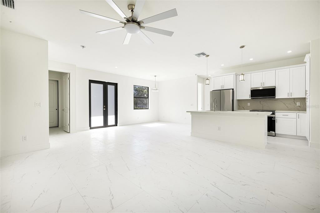 An open-concept kitchen and living area features white cabinetry, marble-look tile flooring, and a ceiling fan — 355 MILTON STREET, PORT CHARLOTTE, FL