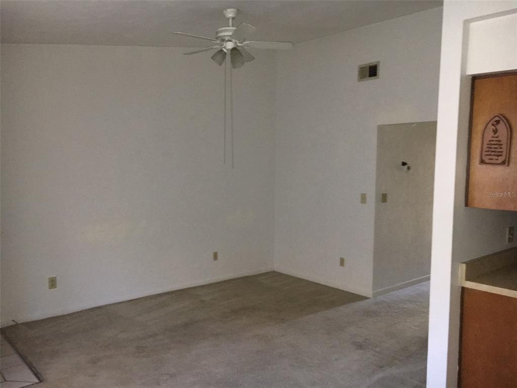 A carpeted living room features a white ceiling fan and a doorway leading to another room — 6735 SW 45TH AVENUE, GAINESVILLE, FL