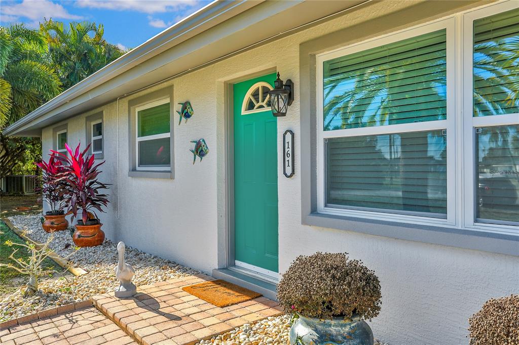 A teal front door with a house number plaque sits on a white stucco exterior — 161 EASTON DRIVE NW, PORT CHARLOTTE, FL