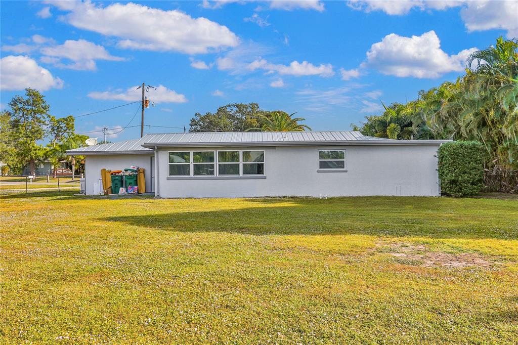 A single-story house with a light gray exterior, metal roof, and a large grassy yard — 161 EASTON DRIVE NW, PORT CHARLOTTE, FL