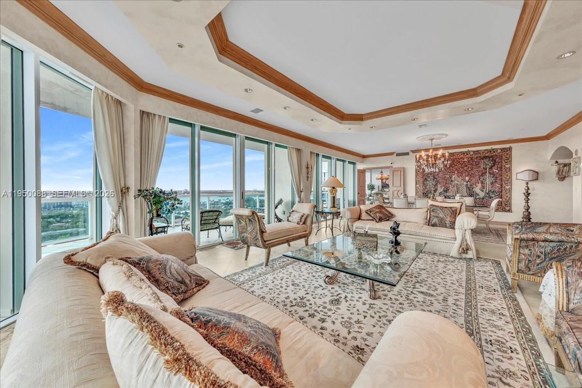 A spacious living room features a coffered ceiling, floor-to-ceiling windows, and traditional furniture — 10101 Collins Ave # 16B, Bal Harbour FL 33154, BAL HARBOUR, FL