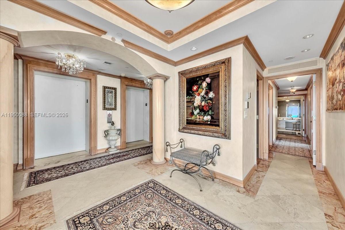 A formal foyer features marble floors, an ornate rug, a crystal chandelier, and an elevator — 10101 Collins Ave # 16B, Bal Harbour FL 33154, BAL HARBOUR, FL