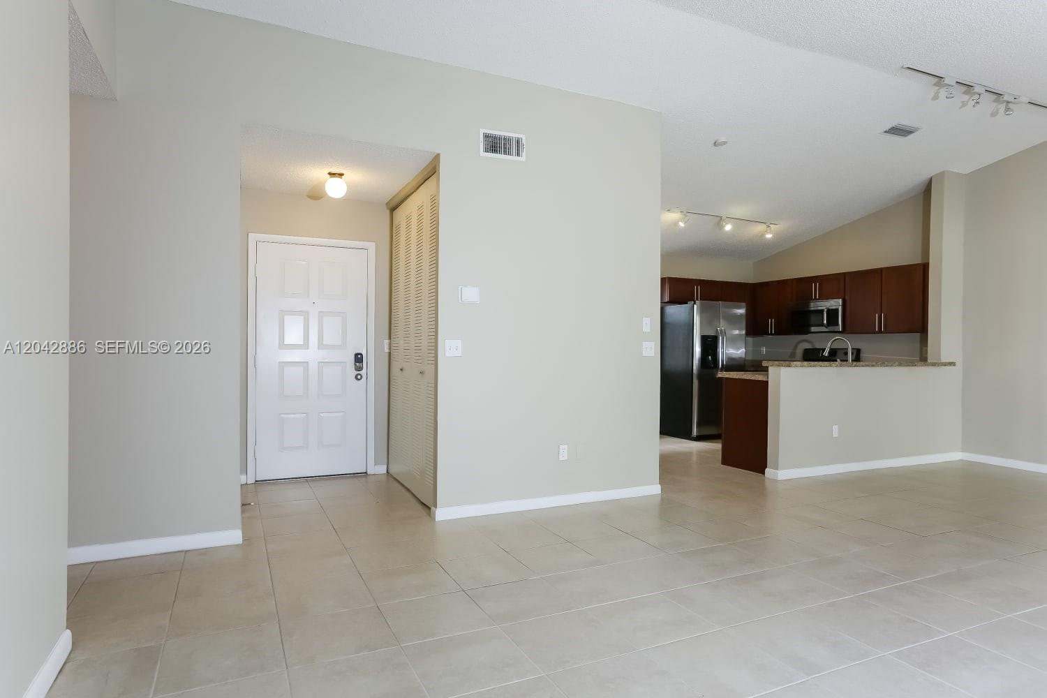 An interior view shows a tiled entryway, a closet, and an open-concept kitchen with cabinets — PLANTATION, FL