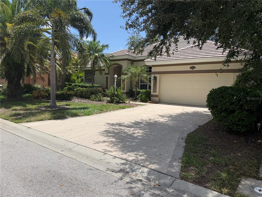 A single-story house with a beige stucco exterior, a tile roof, and a concrete driveway — 6506 WATERS EDGE WAY, BRADENTON, FL