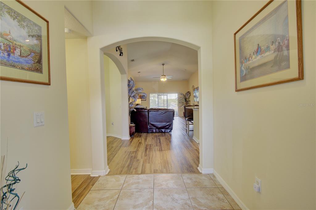 A tiled entryway leads through an arched doorway into a living room with wood flooring — 4834 HAVILLAND DRIVE, MOUNT DORA, FL