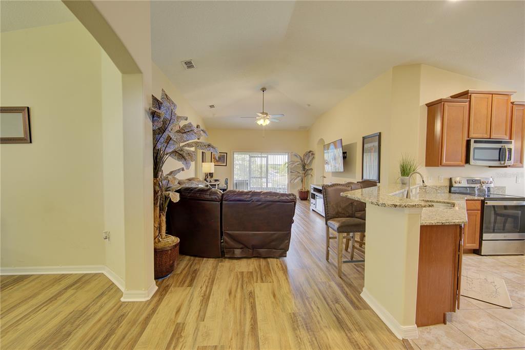 An open-concept living room and kitchen area with wood-look flooring and granite countertops — 4834 HAVILLAND DRIVE, MOUNT DORA, FL