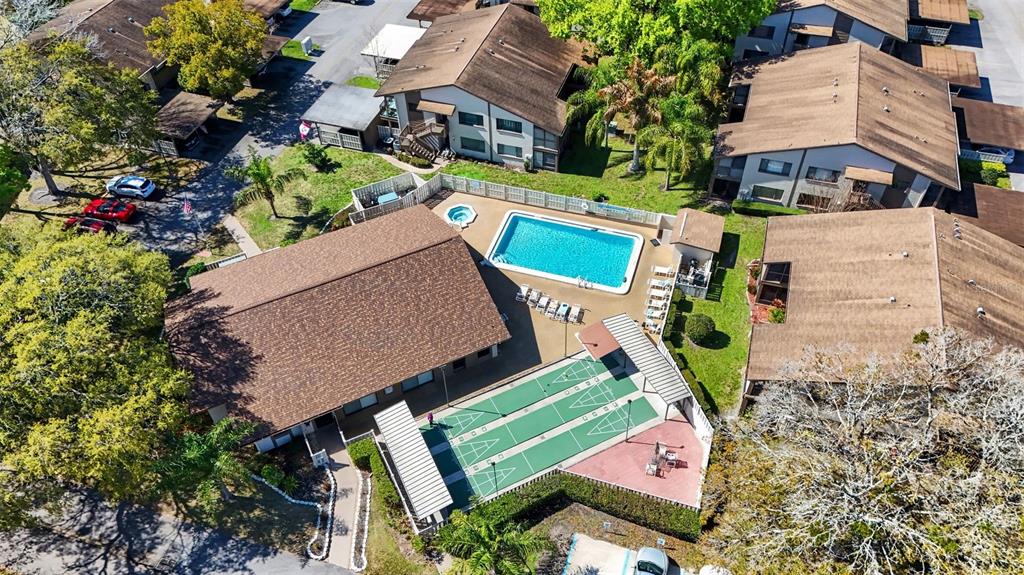 An aerial view shows a community pool, shuffleboard courts, and surrounding apartment buildings — 13006 WEDGEWOOD WAY UNIT D, HUDSON, FL