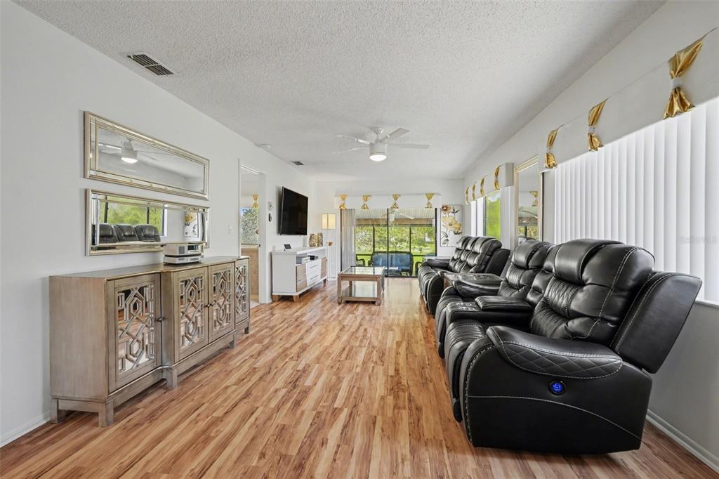 A living room features wood-look flooring, black leather reclining chairs, and a mirrored console table — 13006 WEDGEWOOD WAY UNIT D, HUDSON, FL