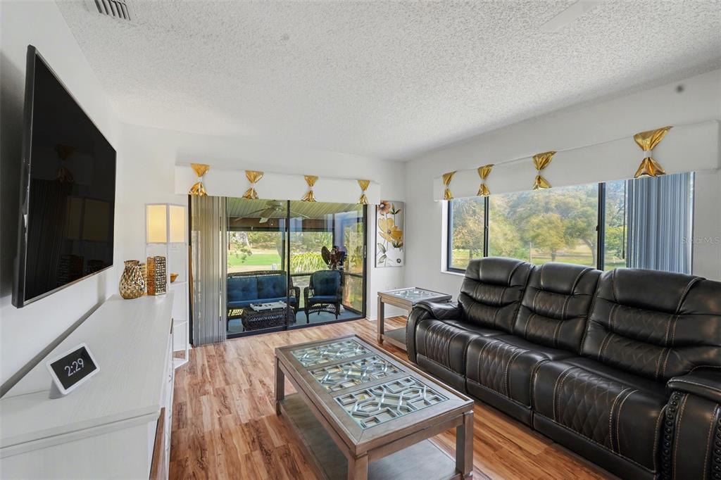 A living room features a black leather sofa, a coffee table, and a sliding door — 13006 WEDGEWOOD WAY UNIT D, HUDSON, FL