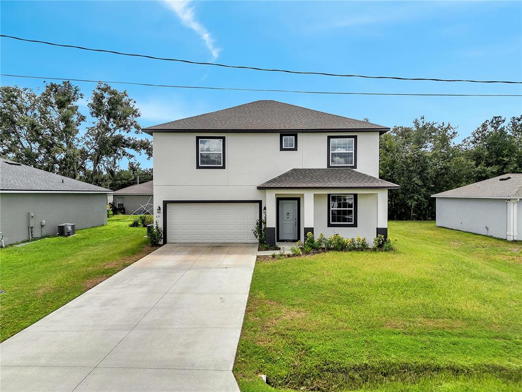 A two-story house with a white stucco exterior, dark trim, and a two-car garage — 651 PARAKEET COURT, KISSIMMEE, FL